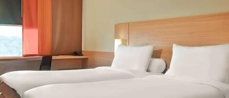 Habitación de hotel con dos camas, cabecero de madera, mesita de noche y ventana con cortinas.