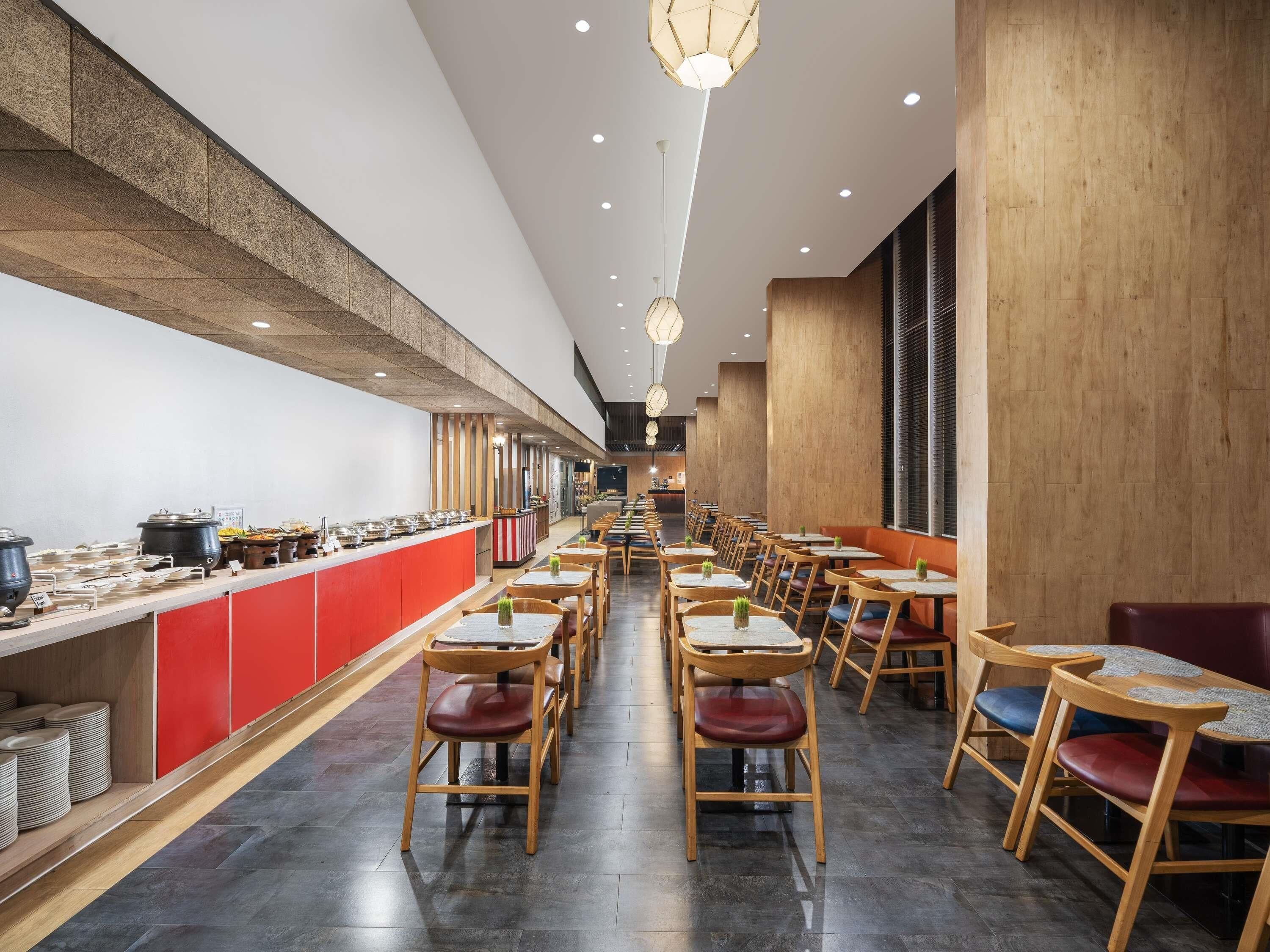 En moderne restaurant med en lang disk, træstole og en rød accentvæg.