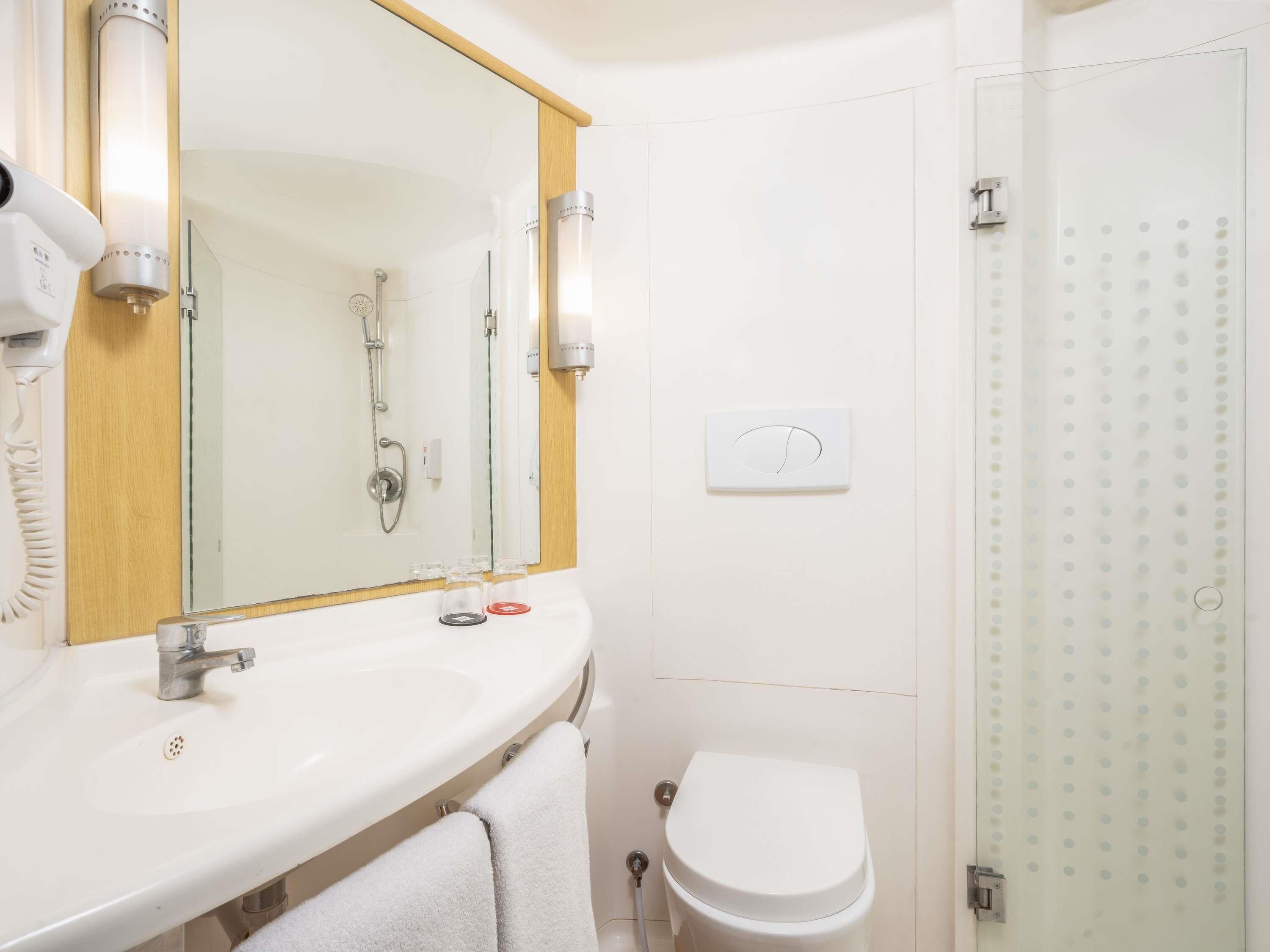 A bathroom with a white sink, mirror, and toilet.
