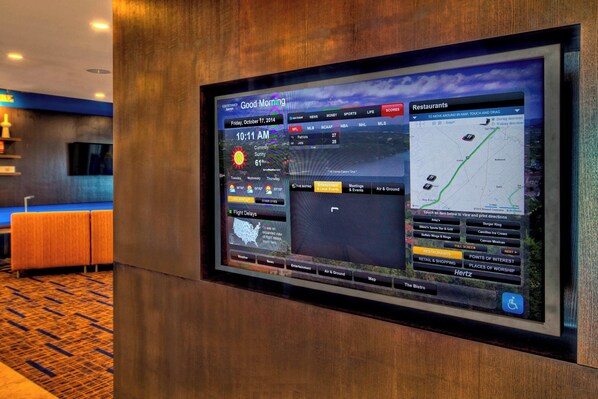 Pantalla digital en el vestíbulo de un hotel que muestra un pronóstico del tiempo, eventos locales y un mapa.