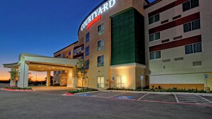 A Courtyard by Marriott hotel with a covered entrance, parking spaces, and a landscaped area. - Courtyard San Marcos (San Marcos)