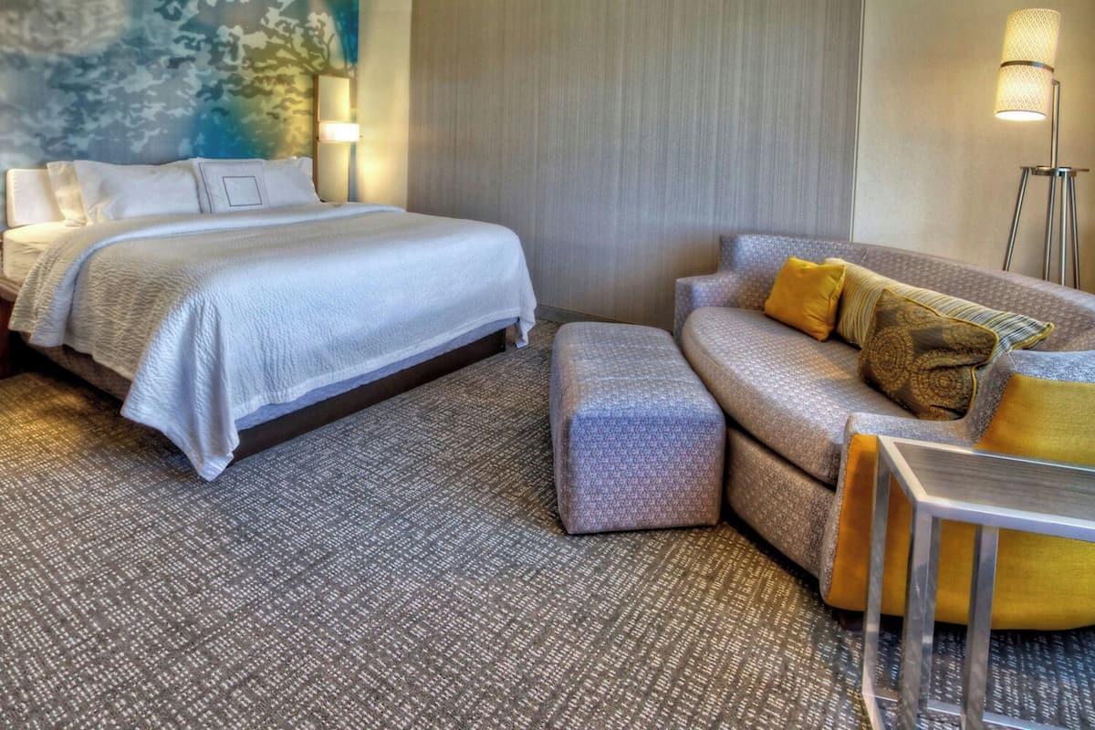 A hotel room with a large bed, a sofa, and a small table.