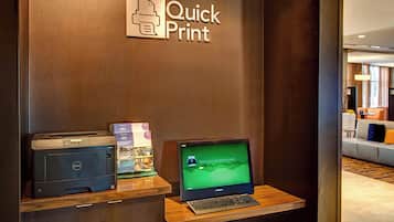 Um balcão de recepção com uma impressora Dell e um laptop mostrando um cartão de embarque.