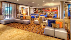 A modern hotel lobby with a seating area, a bar, and a view of the outdoors. - Courtyard San Marcos (San Marcos)