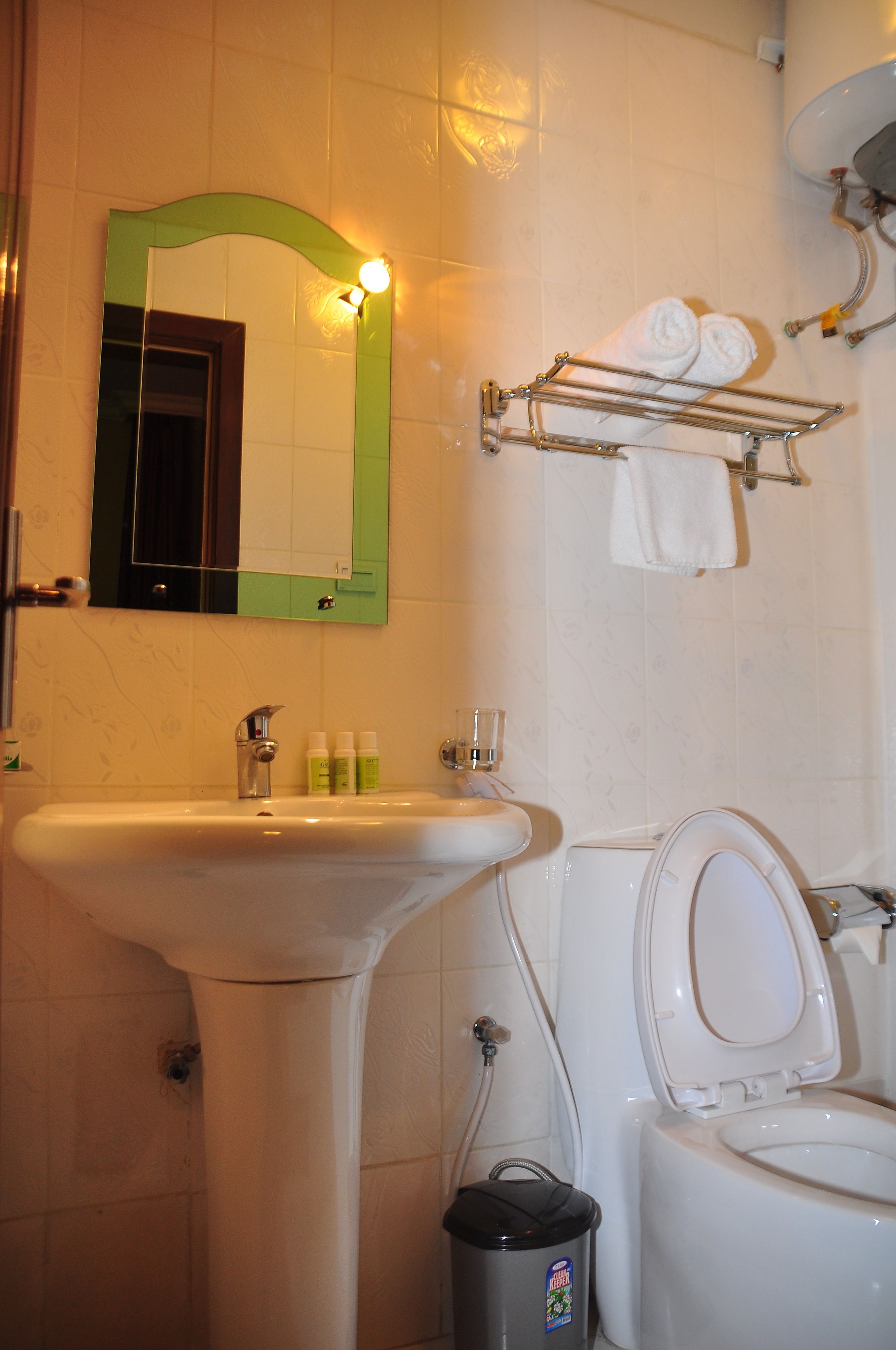 A bathroom with a sink, mirror, toilet, and towel rack.