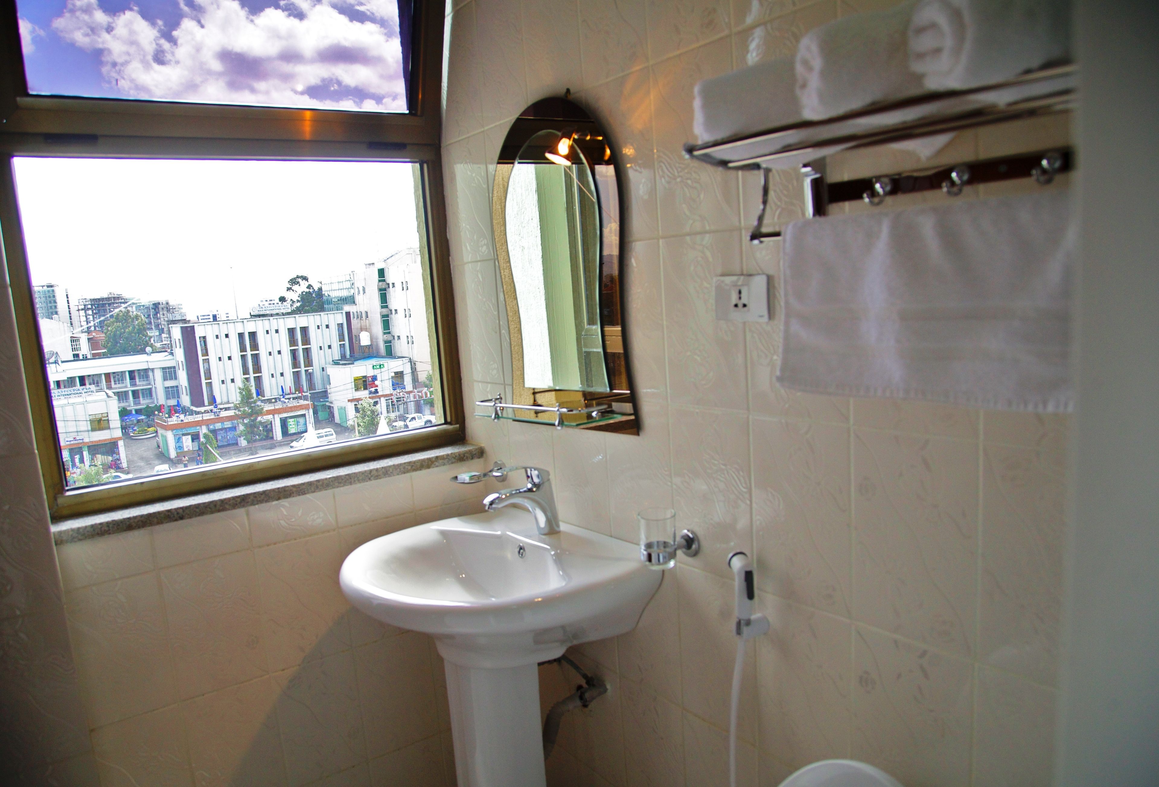 A bathroom with a sink, a mirror, and a window.