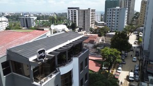 A modern hotel with a rooftop terrace, surrounded by urban buildings and greenery. - Hotel Lobelia (Addis Ababa)