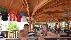 A wooden deck with tables and chairs, a pool table, and a sign reading "BLOODY MARY".
