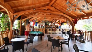 An indoor pool area with wooden beams, pool tables, and seating.