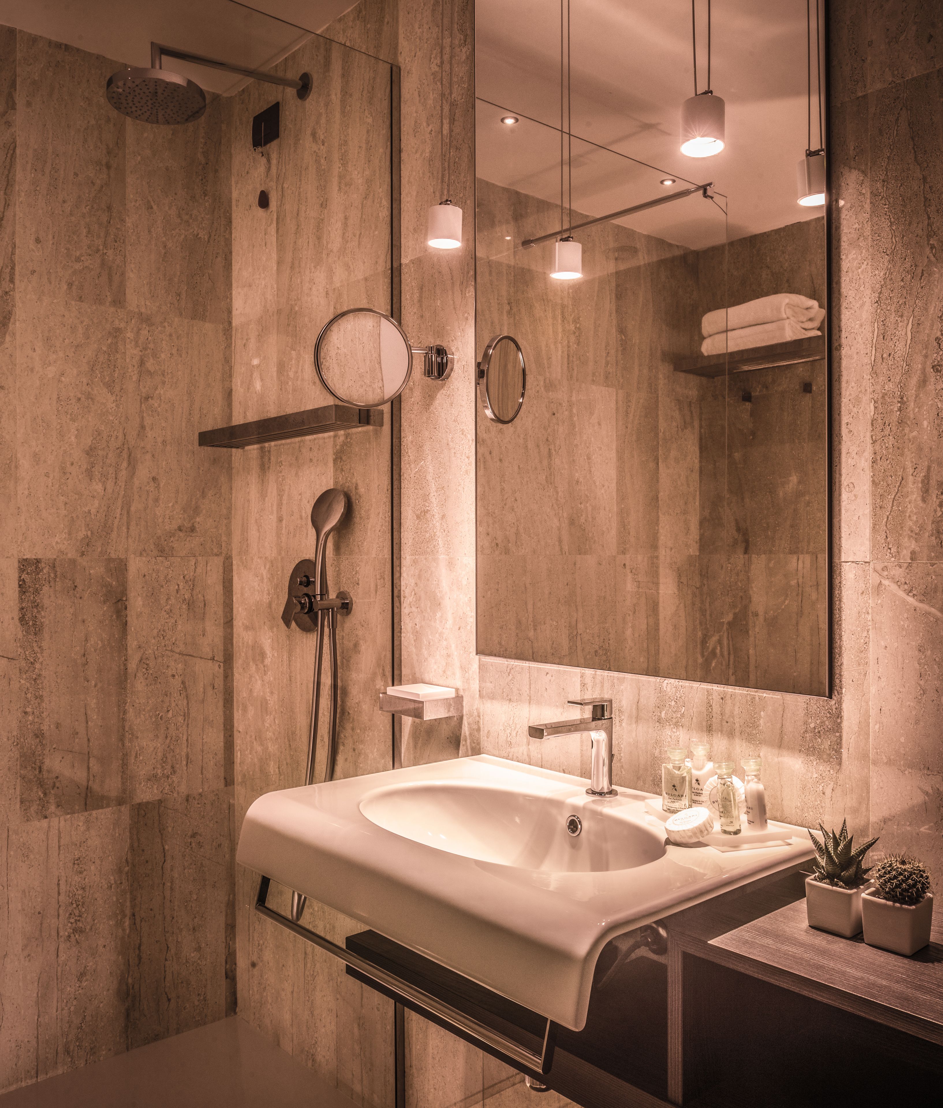 A modern bathroom with a large sink, a mirror, and a shower.