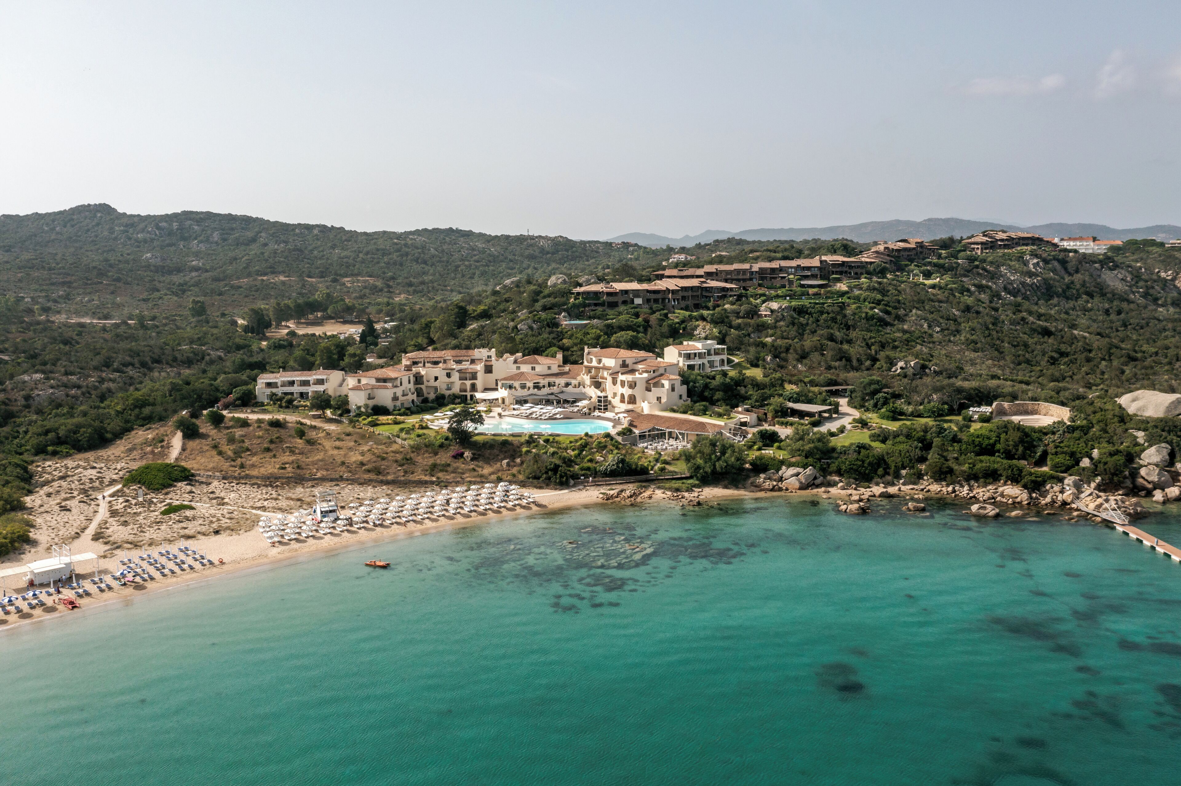 Ein Küstenresort mit Pool, Strand und Bergpanorama.