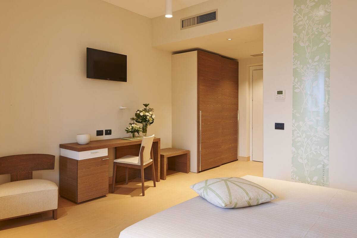 A modern bedroom with a bed, a desk, a chair, and a wardrobe.