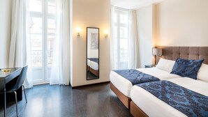 Une chambre d’hôtel avec un lit, un bureau et une chaise.