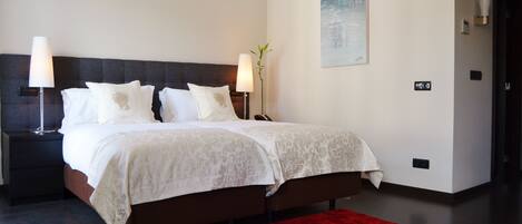 A modern hotel room with a large bed, two bedside lamps, a red rug, and a painting on the wall.