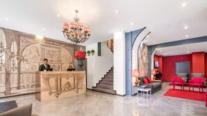 Un hall d’entrée avec un comptoir de réception, un escalier, un canapé et un téléviseur.