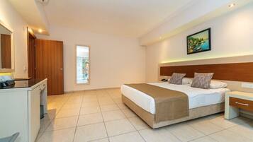 A hotel room with a bed, bedside table, desk, and a window.