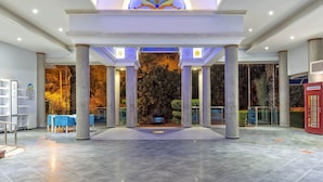 A spacious lobby with a central columned entrance, a clock, and a telephone booth. - Montebello Resort & Spa – All Inclusive (Fethiye)