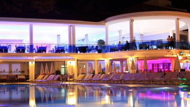 A multi-level hotel with a pool area, lounge chairs, and a dining area. - Montebello Resort & Spa – All Inclusive (Fethiye)