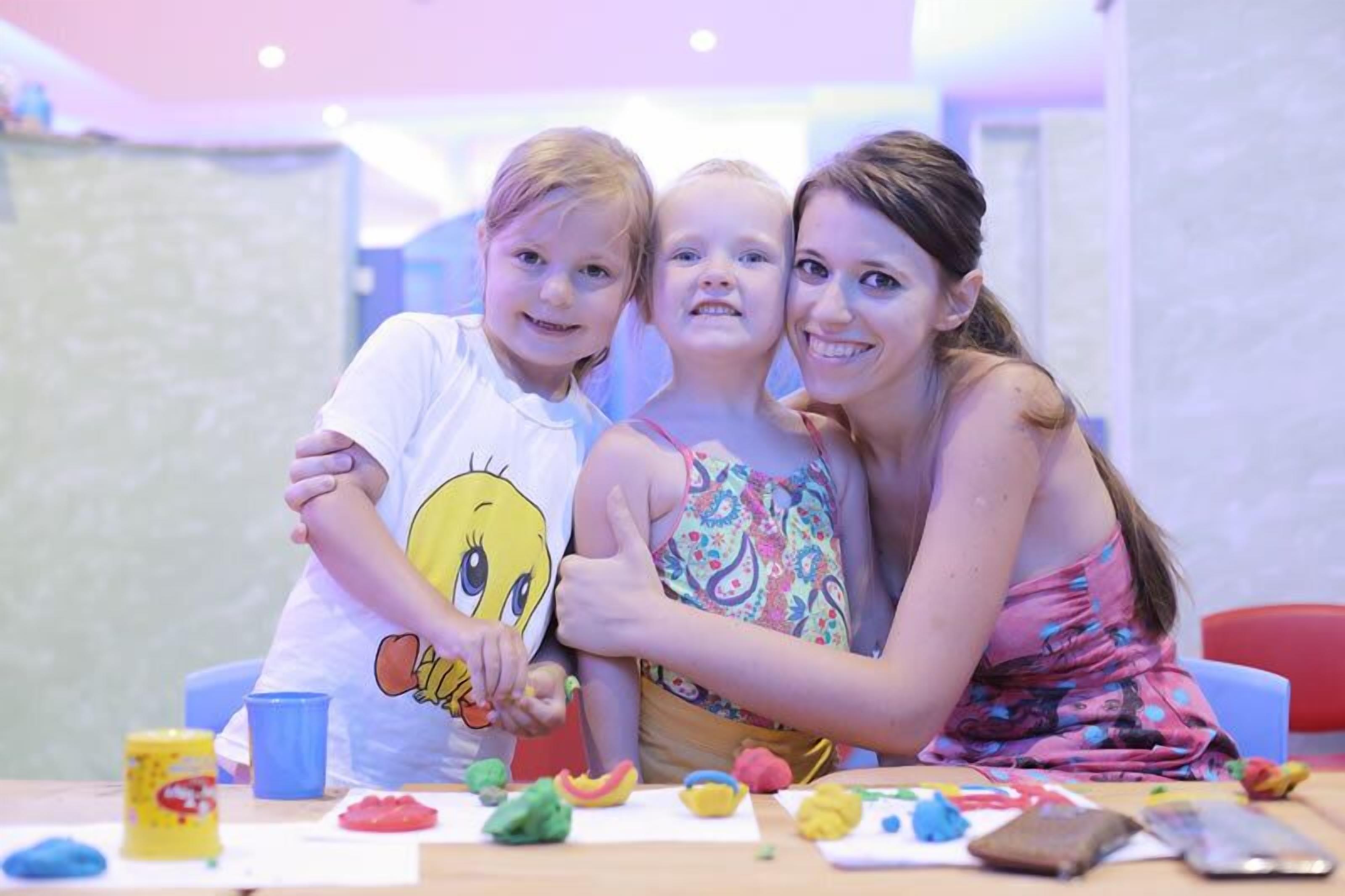 A family of three at a table with various toys and play materials.