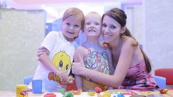 A family of three at a table with various toys and play materials.