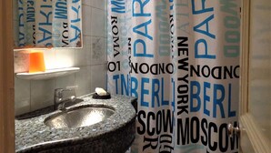Een badkamer met een wastafel van graniet en een spiegel erboven. De wanden zijn betegeld, en er is een handdoekrek te zien.