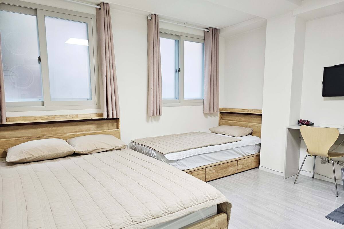 A hotel room with two beds, a desk, and a TV.