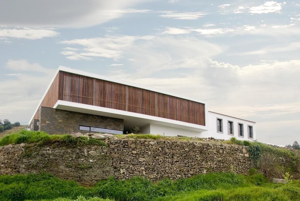 Un edifici modern amb teulada inclinada, base de pedra i panells de fusta.