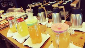 A breakfast buffet with various food items and beverages, including fruit, pastries, and hot beverages.