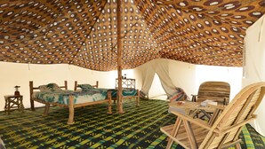 A tent with a patterned floor, a bed, a chair, and a table. - Ecolodge de Lompoul (Lompoul)