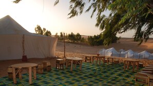 A desert campsite with tents, wooden tables, and a checkered mat. - Ecolodge de Lompoul (Lompoul)