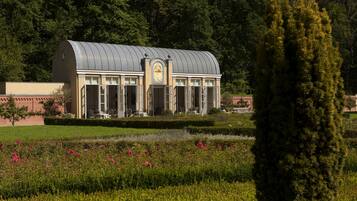 A building with a curved roof, surrounded by a well-maintained garden with various plants and flowers.