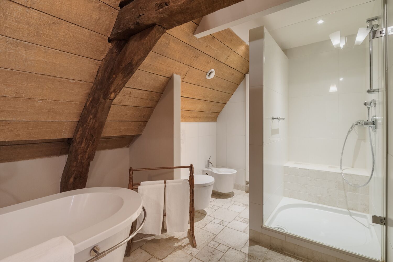 A bathroom with a freestanding bathtub, a glass-enclosed shower, and a wooden ceiling.