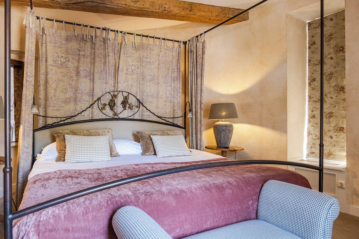 A bedroom with a bed, a nightstand, a lamp, and a window with curtains.