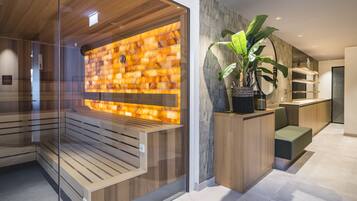 Een moderne receptiebalie met een houten bank, een glazen scheidingswand, een stenen muur en een potplante.