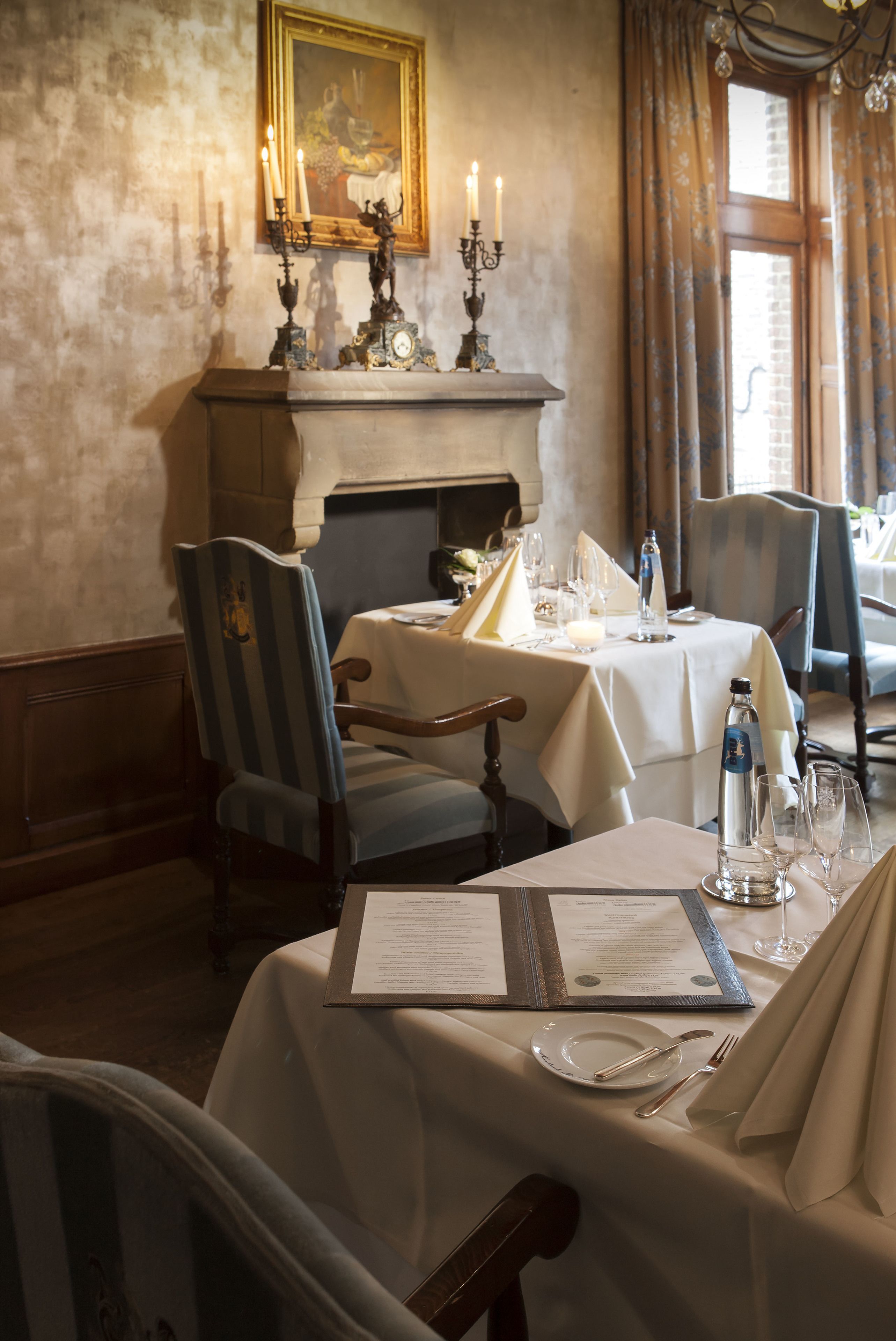 A dining area with a fireplace, table set with candles, and a menu.