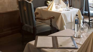 A dining area with a fireplace, table set with candles, and a menu.