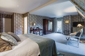 Une chambre d’hôtel avec un grand lit, un bureau, une chaise et un téléviseur.