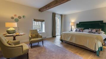 A bedroom with a large bed, a chair, a table with a lamp, and a window with curtains.