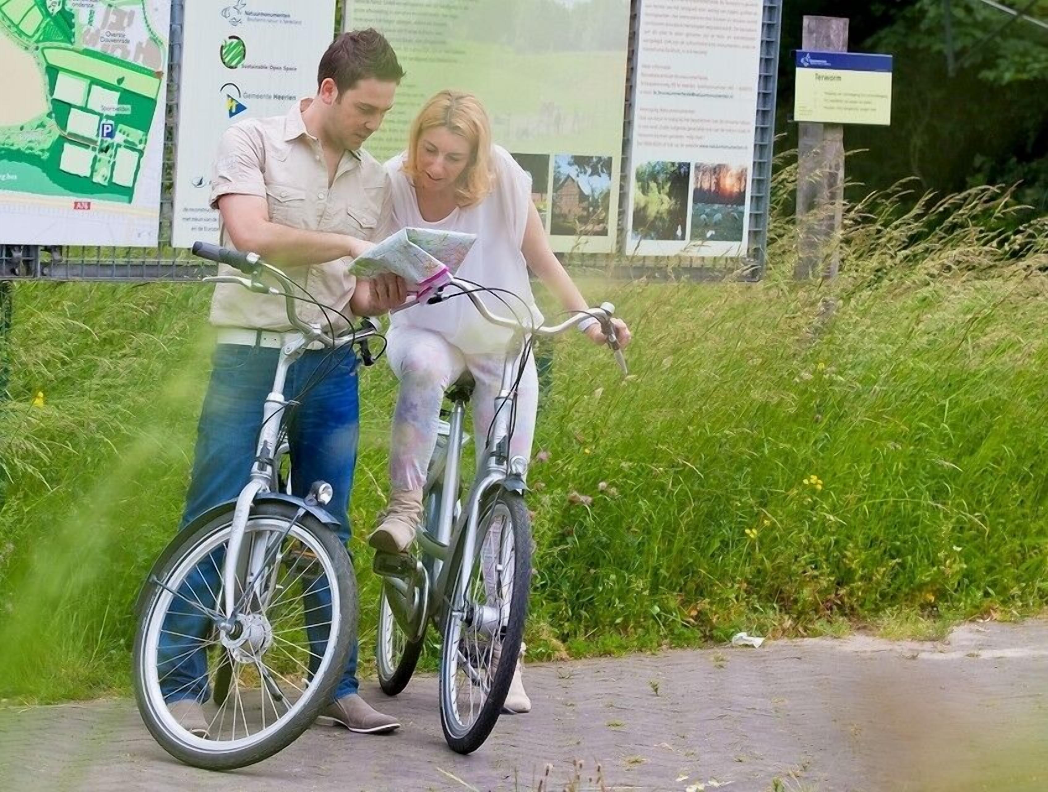 Un home i una dona amb bicicleta, mirant un mapa.