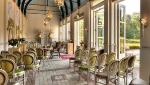 A formal dining room with rows of chairs, a chandelier, and large windows with a view of greenery. - Van der Valk Hotel Kasteel Terworm (Heerlen)