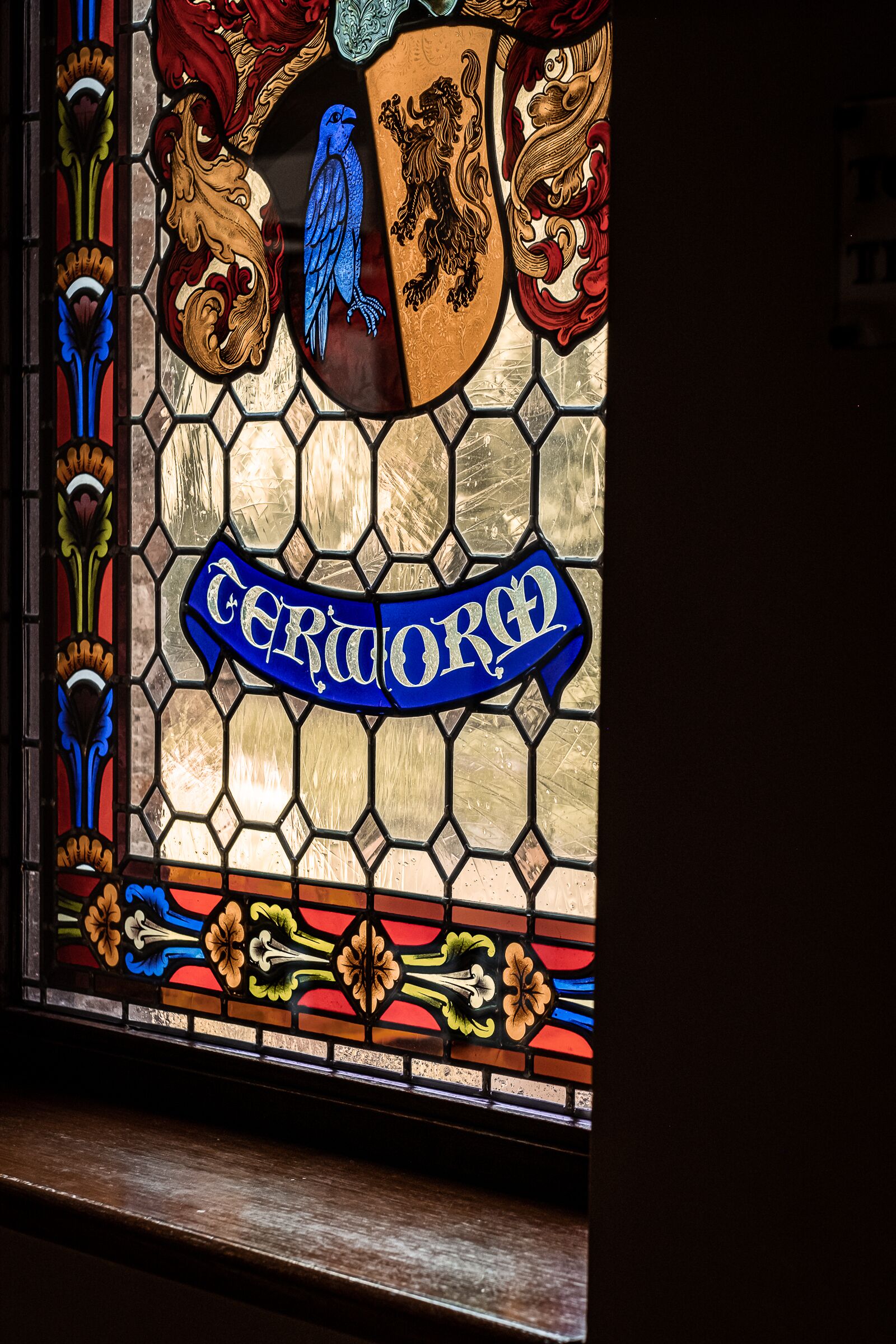 A stained glass window with heraldic designs and the inscription "Certa Ord".