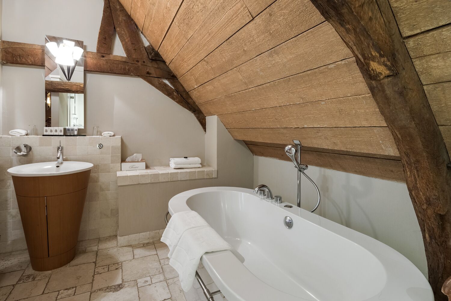 A bathroom with a freestanding bathtub, a sink, and a mirror.