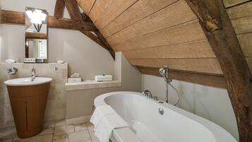 A bathroom with a freestanding bathtub, a sink, and a mirror.