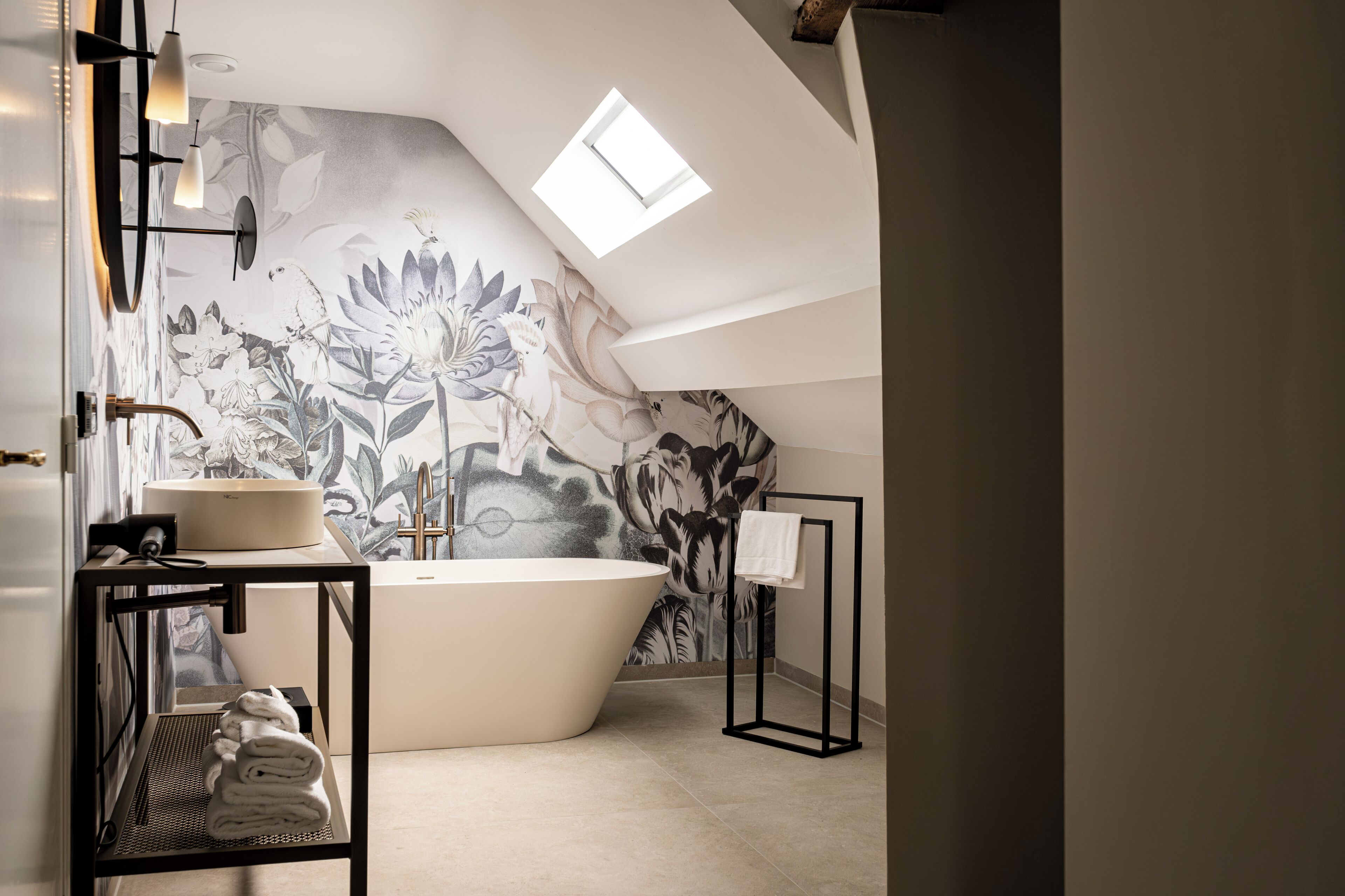 A modern bathroom with a freestanding bathtub, a sink, and a towel rack.