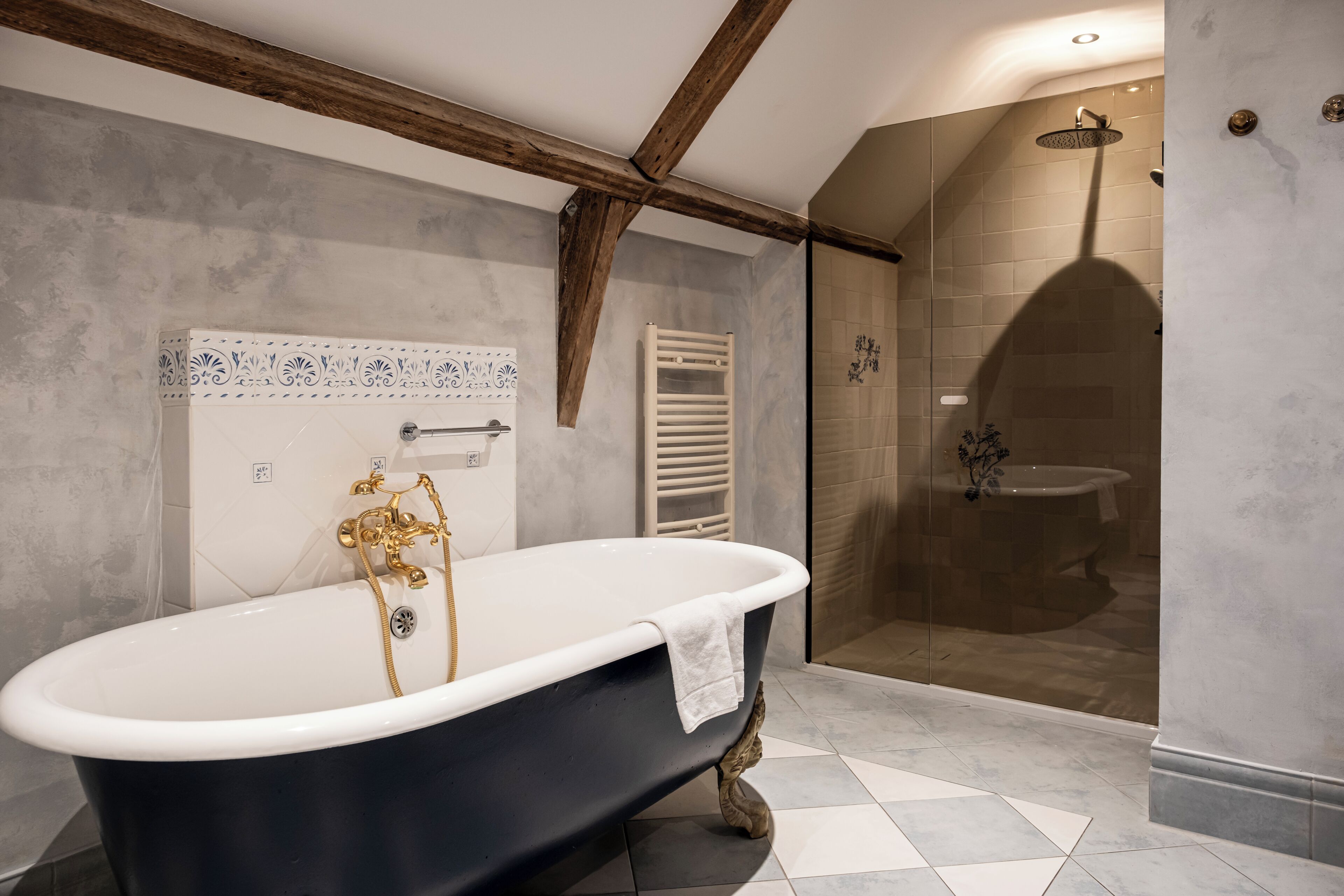 A bathroom with a freestanding bathtub, a glass-enclosed shower, and a tiled floor.