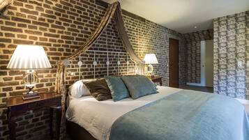 Quarto com parede de tijolos, cama de dossel, duas luminárias de cabeceira e papel de parede estampado na parede vizinha.