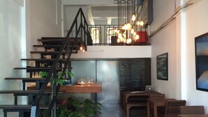A modern interior with a staircase, wooden tables, and potted plants. - Kama Bangkok - Boutique Bed & Breakfast - Hostel (Bangkok)
