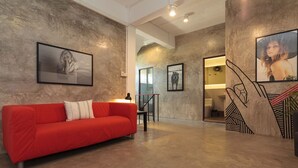 A modern interior with a red sofa, framed artwork, and a staircase with a geometric design. - Kama Bangkok - Boutique Bed & Breakfast - Hostel (Bangkok)
