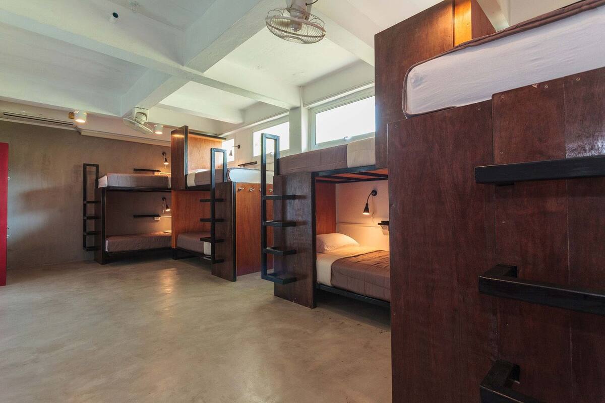 Une chambre avec des lits superposés en bois, une échelle et un petit bureau avec une lampe.