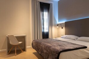 A modern hotel room with a large bed, a desk, and a chair. - Hostal Bcn 46 (Barcelona)